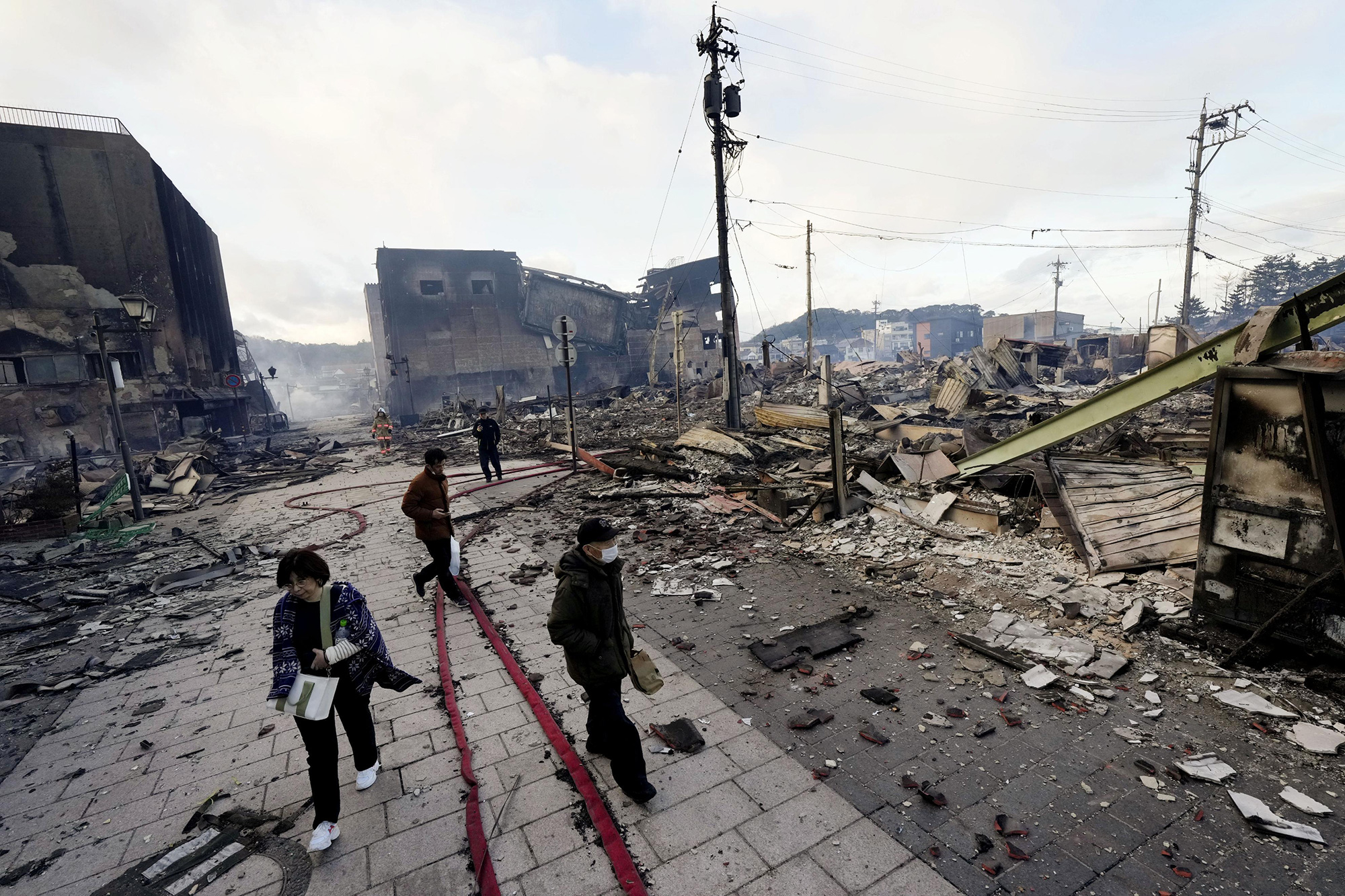 People walk past the rubble of a market in Wajima, Ishikawa prefecture, on January 2. 